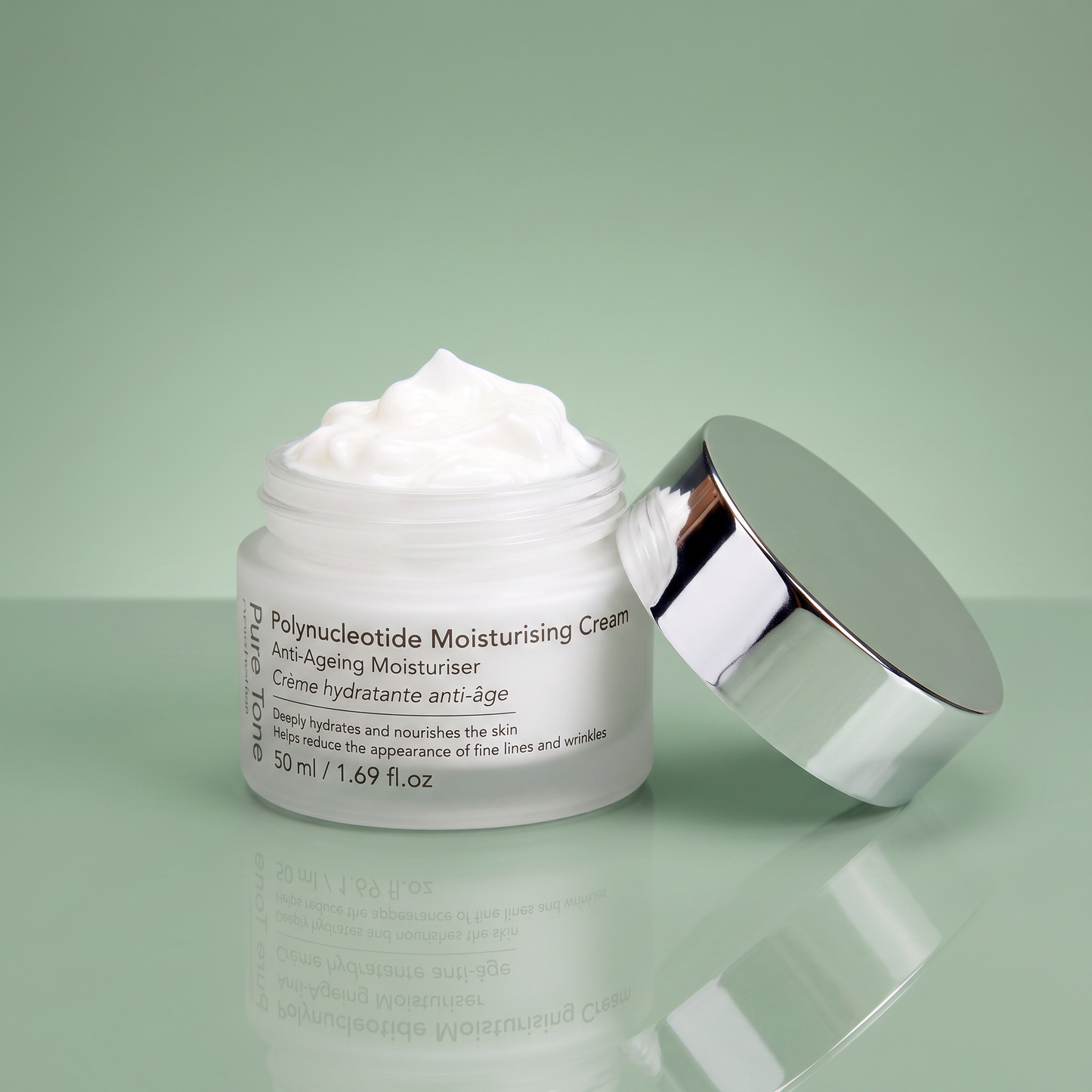 Open jar of Pure Tone Aesthetics Polynucleotide Moisturising Cream with the silver lid resting beside it on a reflective green surface