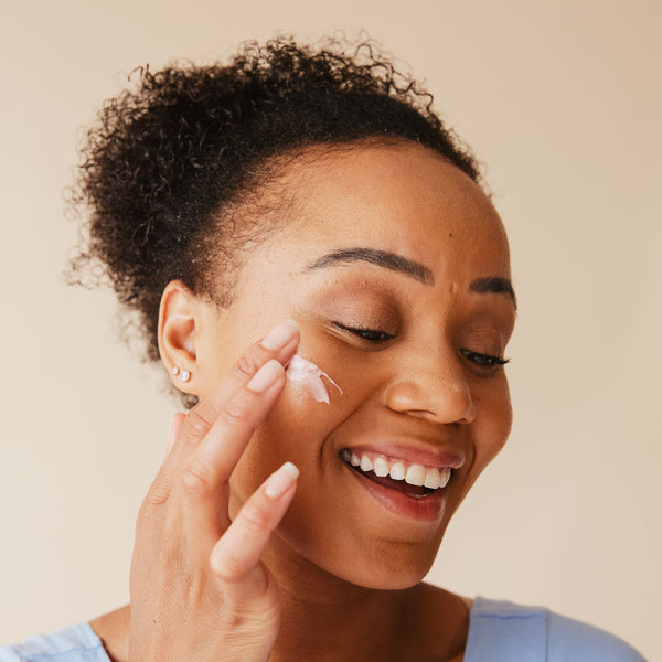 Lady applying moisturiser with a big smile on her face